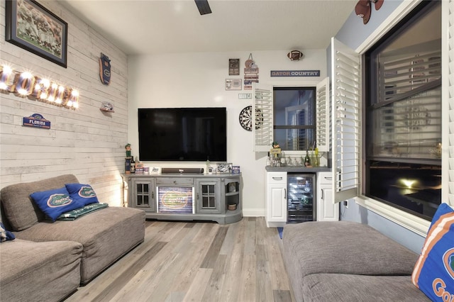 living room featuring indoor bar, light hardwood / wood-style flooring, wine cooler, and wood walls