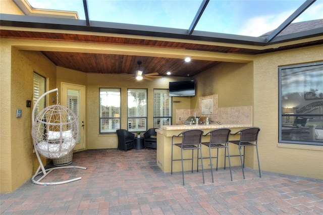 view of patio with ceiling fan, a lanai, and an outdoor bar