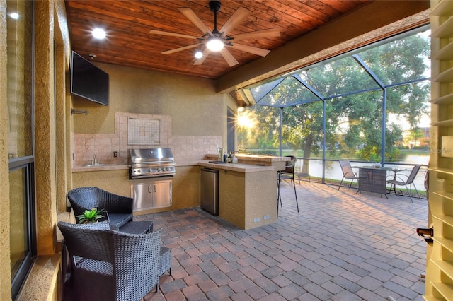 view of patio featuring grilling area, an outdoor kitchen, ceiling fan, a lanai, and a wet bar