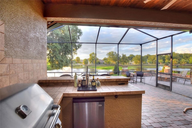 view of patio featuring glass enclosure, area for grilling, and a water view