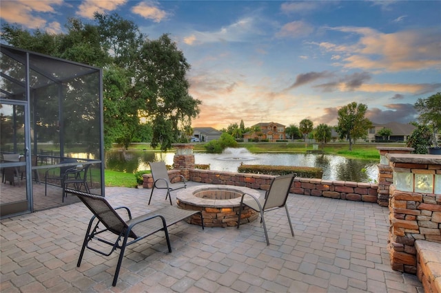 patio terrace at dusk featuring a lanai and a water view