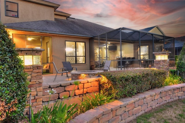 back house at dusk featuring a patio, an outdoor fire pit, and a lanai