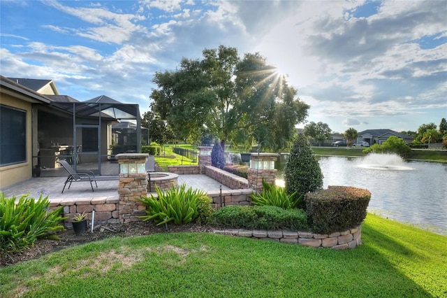 view of yard with glass enclosure, a water view, and a patio