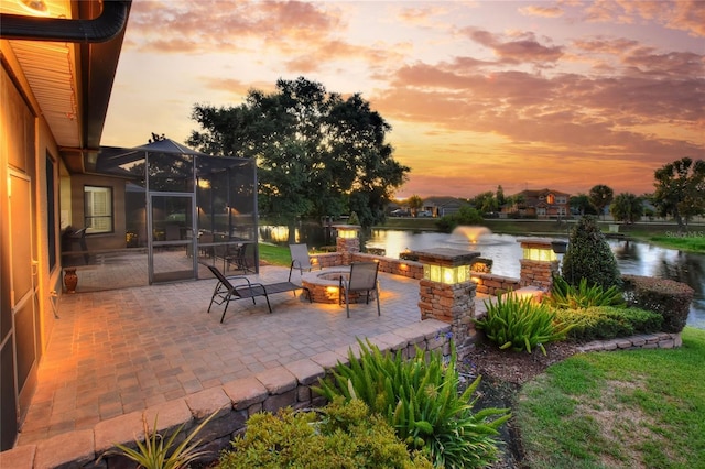 patio terrace at dusk featuring a water view and a fire pit