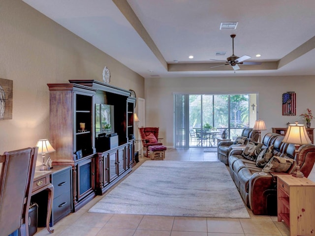 living room with a raised ceiling, ceiling fan, and light tile patterned floors