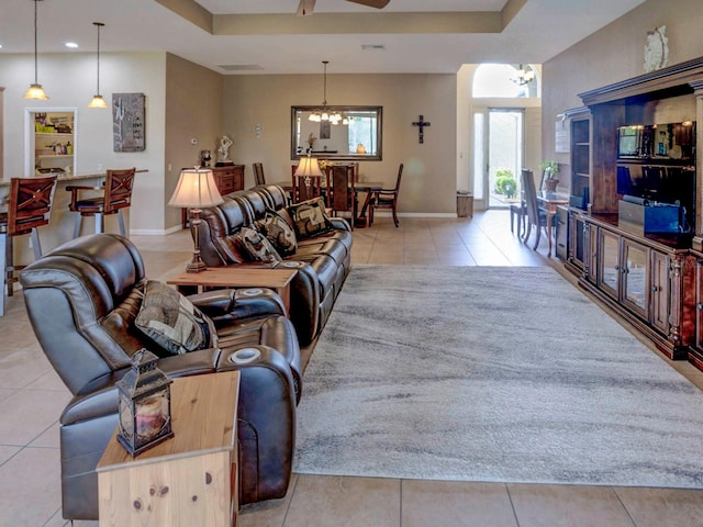 living room with a tray ceiling and light tile patterned floors