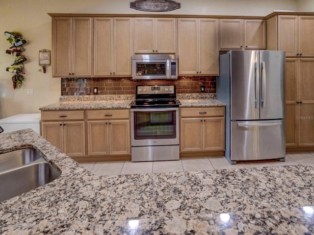 kitchen featuring decorative backsplash, appliances with stainless steel finishes, light stone counters, sink, and light tile patterned flooring