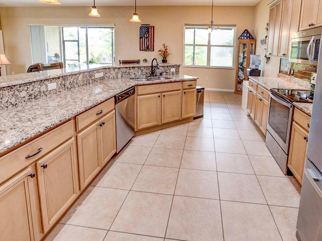 kitchen with light stone countertops, sink, hanging light fixtures, light tile patterned floors, and appliances with stainless steel finishes