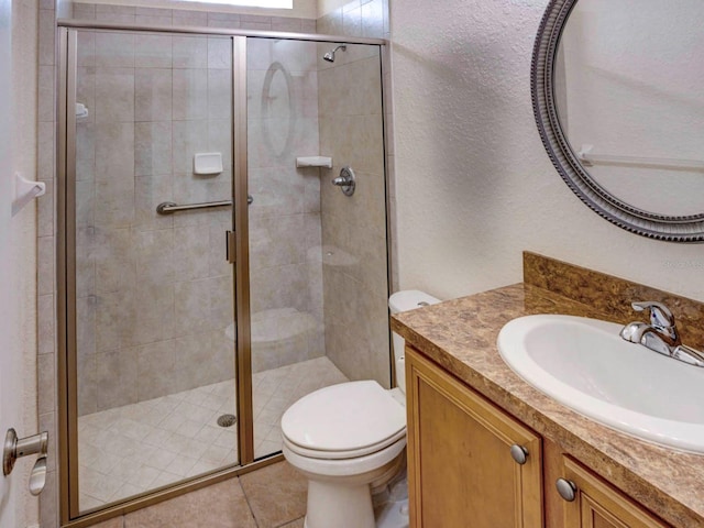 bathroom with tile patterned flooring, vanity, toilet, and a shower with shower door