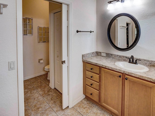 bathroom with tile patterned flooring, vanity, and toilet