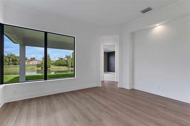 unfurnished room with a water view, crown molding, and hardwood / wood-style flooring