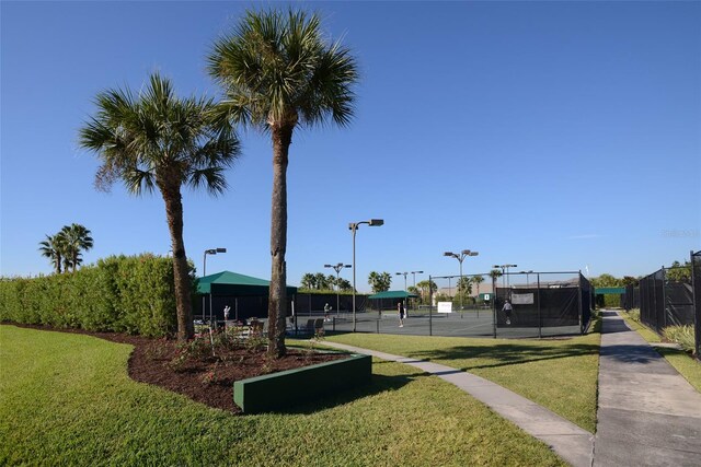 view of home's community with a lawn and tennis court