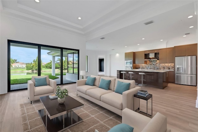 living room featuring ornamental molding, light hardwood / wood-style floors, and a raised ceiling