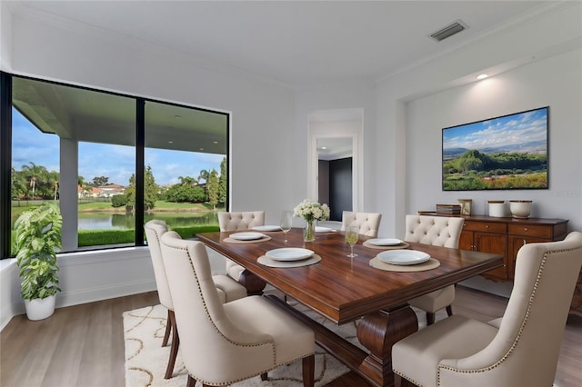 dining area featuring a water view, crown molding, and hardwood / wood-style flooring