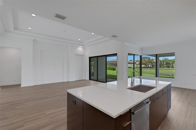 kitchen with a kitchen island with sink, stainless steel dishwasher, a raised ceiling, and sink