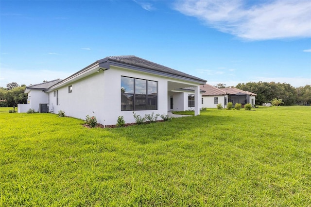 rear view of property with a lawn and central AC