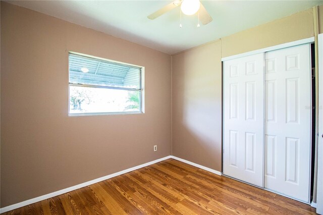 unfurnished bedroom featuring ceiling fan, wood-type flooring, and a closet