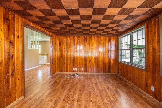 spare room with light wood-type flooring and wood walls