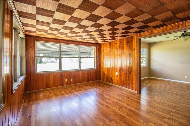 empty room featuring wood walls, ceiling fan, and dark hardwood / wood-style flooring