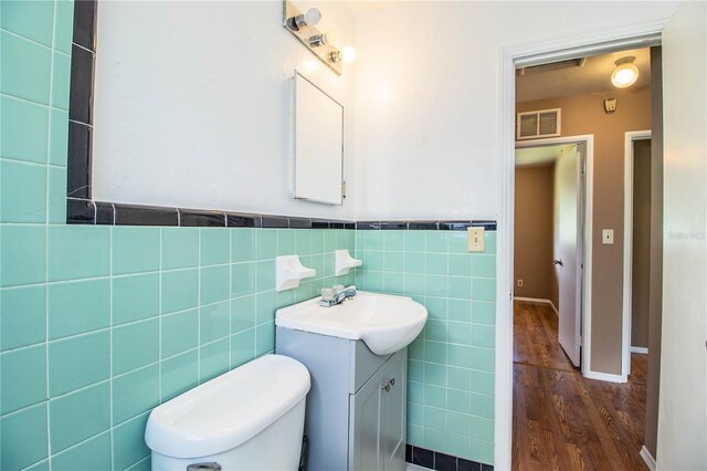 bathroom with tile walls, vanity, hardwood / wood-style floors, and toilet