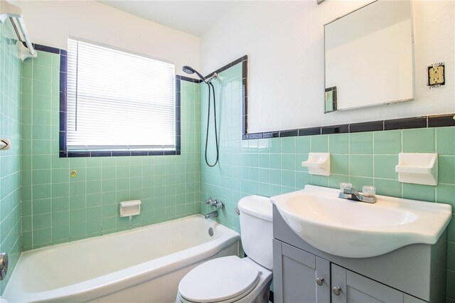 full bathroom featuring backsplash, vanity, tiled shower / bath, tile walls, and toilet