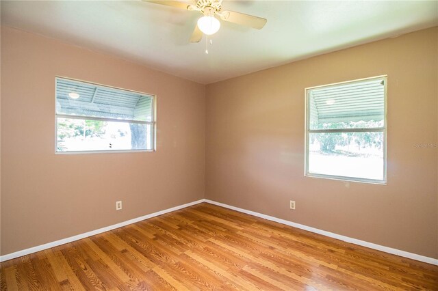 empty room with plenty of natural light, ceiling fan, and wood-type flooring