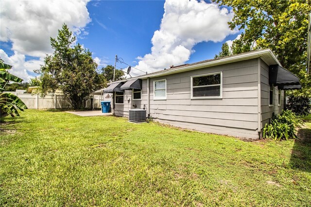 back of property featuring central AC unit and a lawn