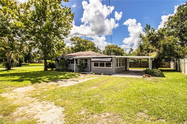 rear view of property featuring a lawn and a carport