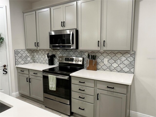 kitchen with stainless steel appliances, gray cabinets, and decorative backsplash