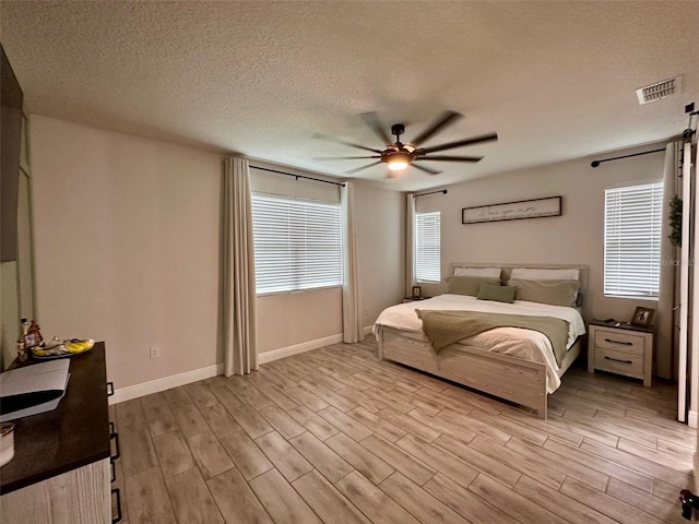 bedroom with ceiling fan, light wood-type flooring, and a textured ceiling