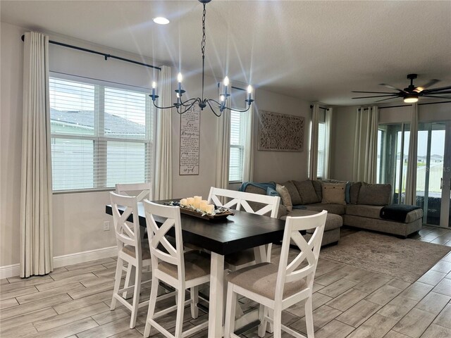 dining space with ceiling fan with notable chandelier, light hardwood / wood-style flooring, and plenty of natural light