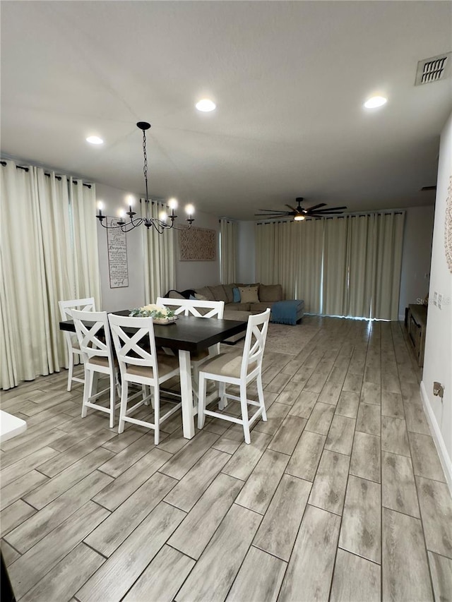 dining room with light hardwood / wood-style flooring and ceiling fan with notable chandelier