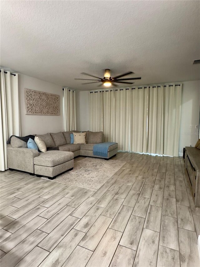 unfurnished living room with ceiling fan, light hardwood / wood-style floors, and a textured ceiling