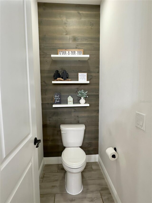 bathroom featuring wooden walls and toilet