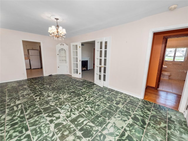 empty room featuring french doors and a notable chandelier