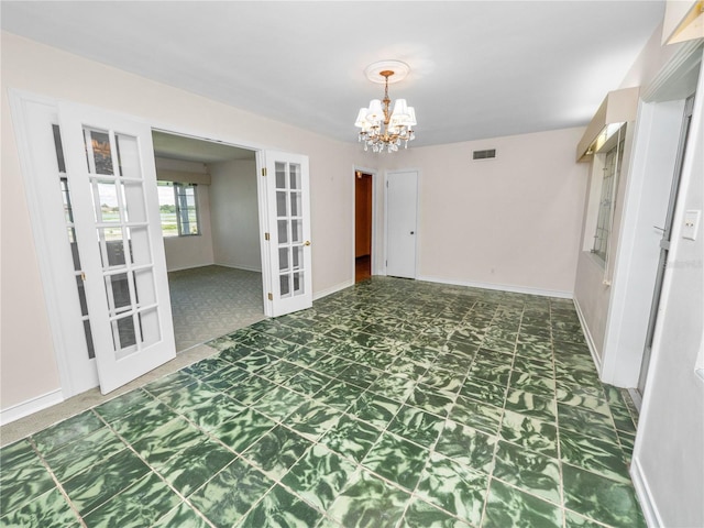 spare room with french doors and an inviting chandelier