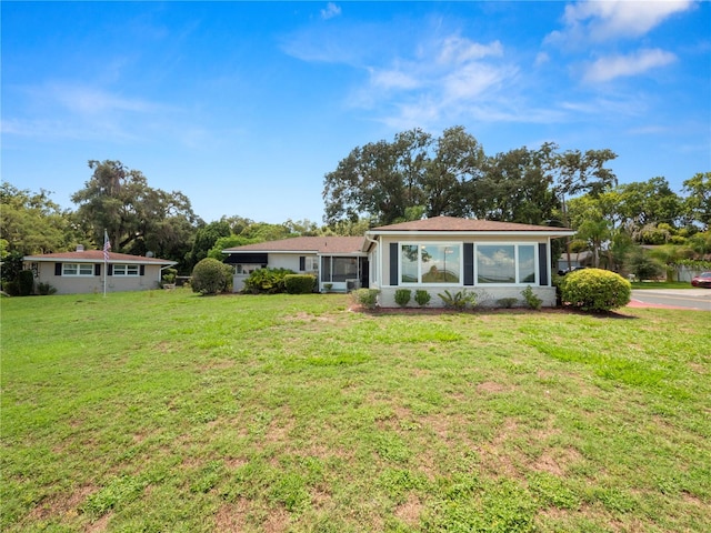 ranch-style home featuring a front lawn and a sunroom