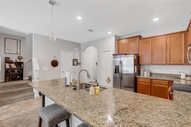 kitchen with stainless steel fridge with ice dispenser, a breakfast bar area, light tile patterned floors, hanging light fixtures, and sink