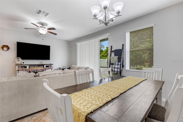 tiled dining room with ceiling fan with notable chandelier