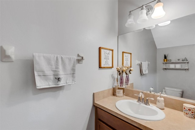 bathroom featuring vaulted ceiling, toilet, and vanity