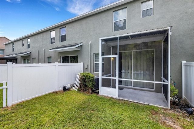 back of property featuring a sunroom and a lawn