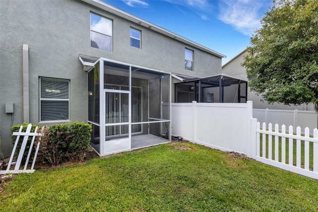 rear view of property featuring a sunroom and a yard