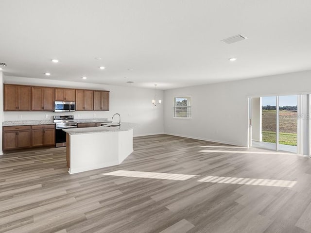 kitchen featuring stainless steel appliances, a center island with sink, and light hardwood / wood-style floors