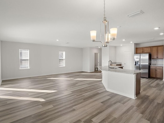 kitchen with decorative light fixtures, plenty of natural light, stainless steel fridge with ice dispenser, and a chandelier