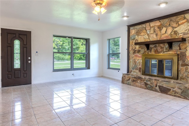 unfurnished living room with ceiling fan, light tile patterned flooring, a fireplace, and a textured ceiling