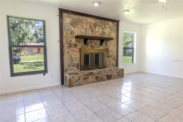 unfurnished living room with light tile patterned flooring and a stone fireplace