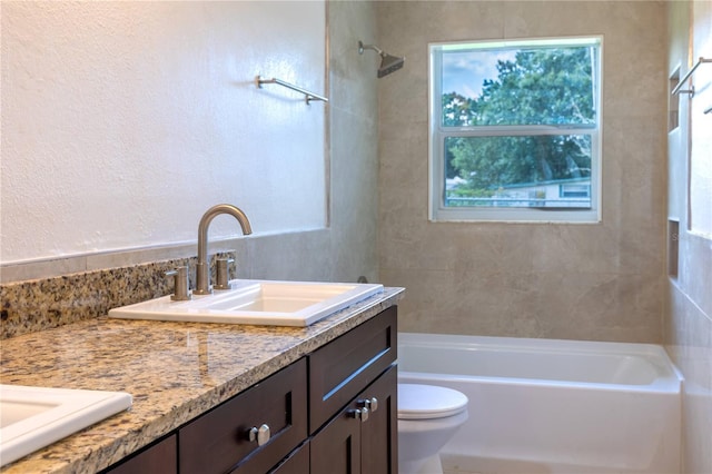 full bathroom featuring a healthy amount of sunlight, tiled shower / bath, vanity, and toilet