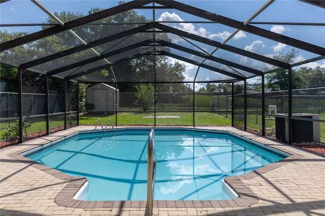 view of pool featuring a lanai, a patio, a lawn, and a storage shed