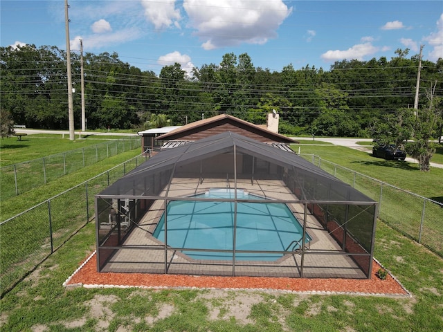 view of swimming pool with a patio, glass enclosure, and a lawn