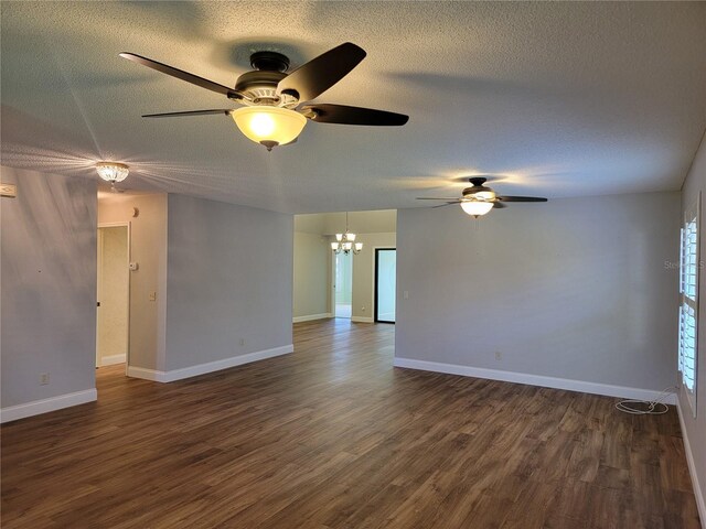 empty room with a textured ceiling, ceiling fan with notable chandelier, and dark wood-type flooring